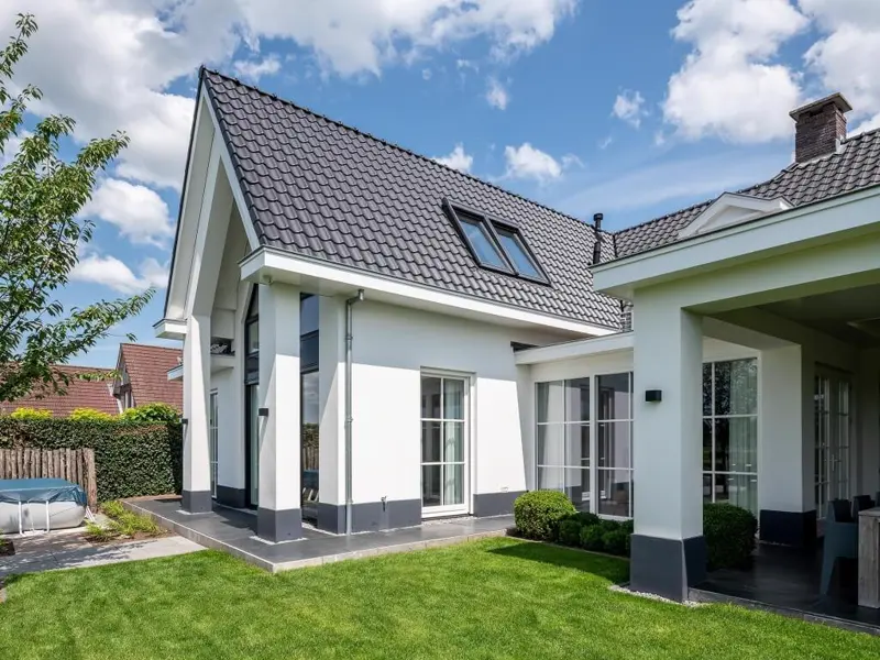 Witte woning met donker pannendak en dakkapellen